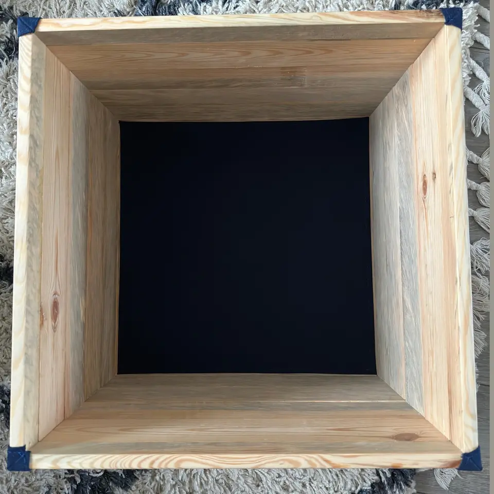 Intérieur du pouf-coffre sur mesure ouvert : caisse en bois massif et fond habillé d'une toile noire tendue