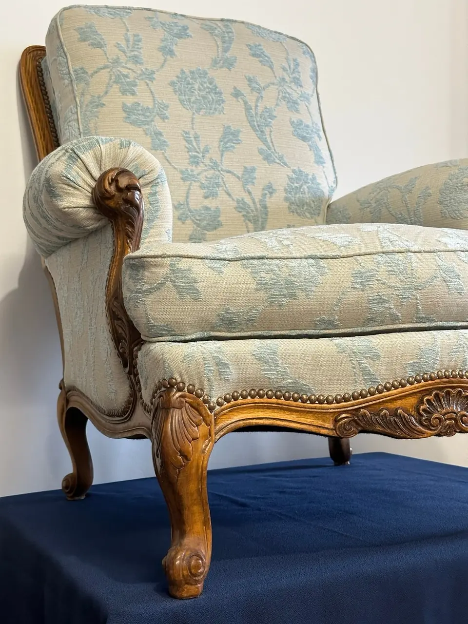 Bergère ancienne entièrement regarnie et recouverte d'un tissu fleuri bleu sur fond clair