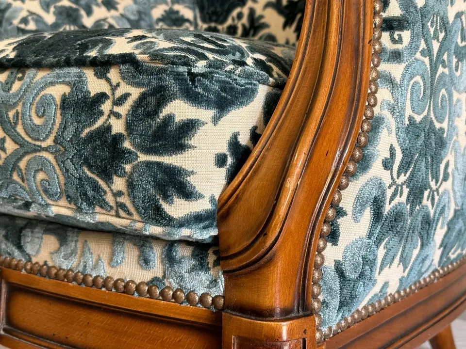 Détail du dossier d'un fauteuil ancien recouvert d'un jacquard bleu et blanc, finition clous