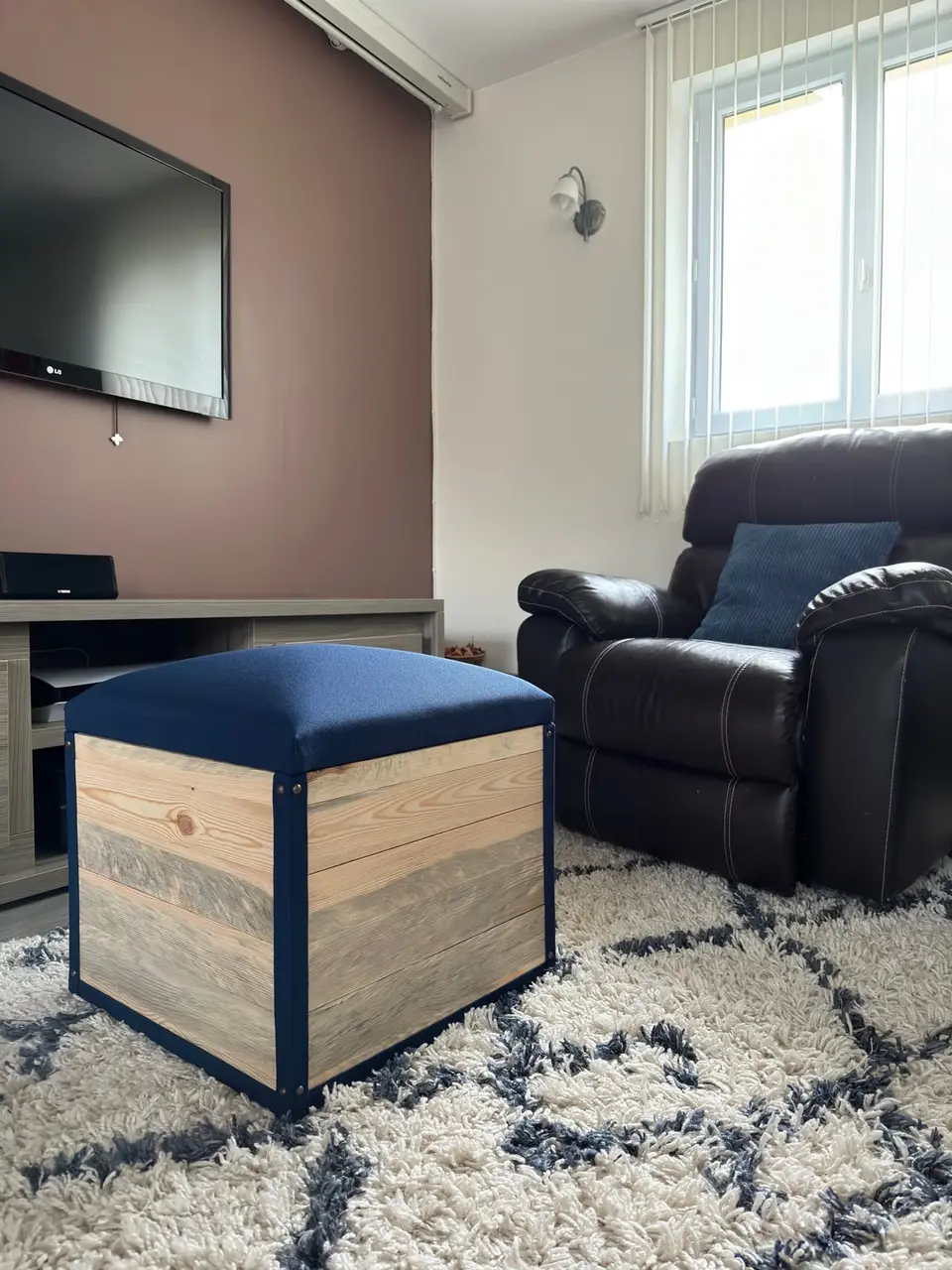 Pouf-coffre sur mesure en bois brut avec assise garnie en tissu bleu nuit, fabriqué à l'atelier