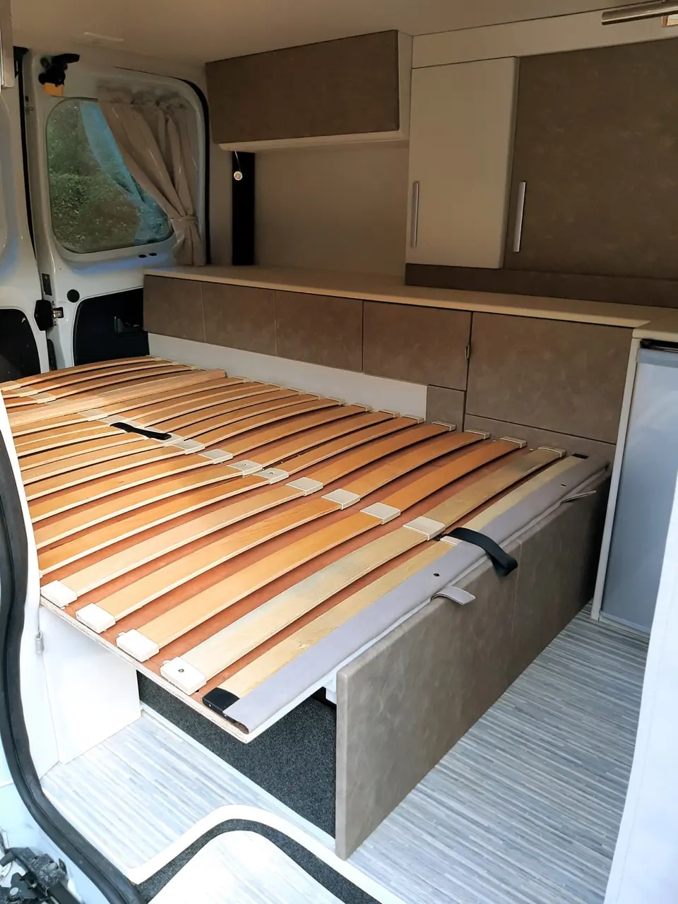 Sommier à lattes de bois déployé dans un van aménagé, transformation banquette-lit