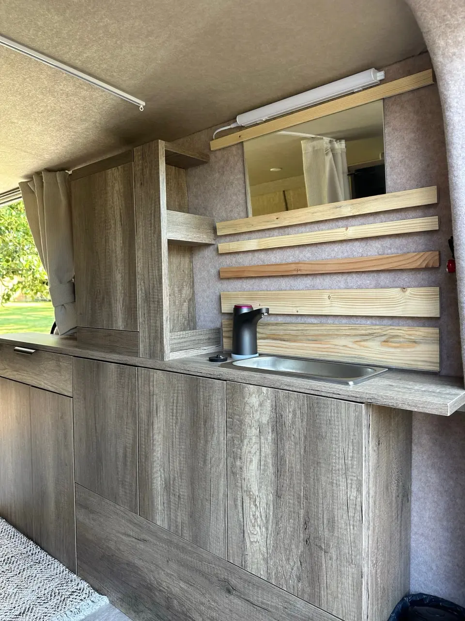 Meuble de cuisine en bois clair d'un van aménagé, conçu et fabriqué à l'atelier en 2023